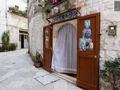 Aspetto simile ce l�ha un�altra casetta di strada Quercia, arricchita anche da piattini e quadretti e incorniciata da un arco in pietra. L�uscio di entrambe � protetto con una bianca e delicata tenda di pizzo: un �must� per i sottani
